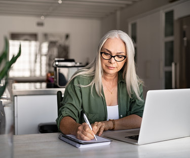 Woman taking detailed notes from laptop